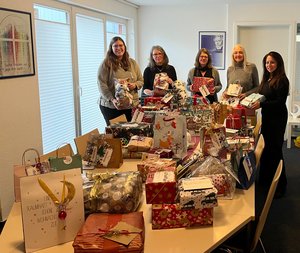 Fünf Mitarbeiterinnen der Diakonie im Oldernburger Münsterland stehen an einem Tisch auf dem sehr viele gespendete Weihnachtsgeschenke liegen. 